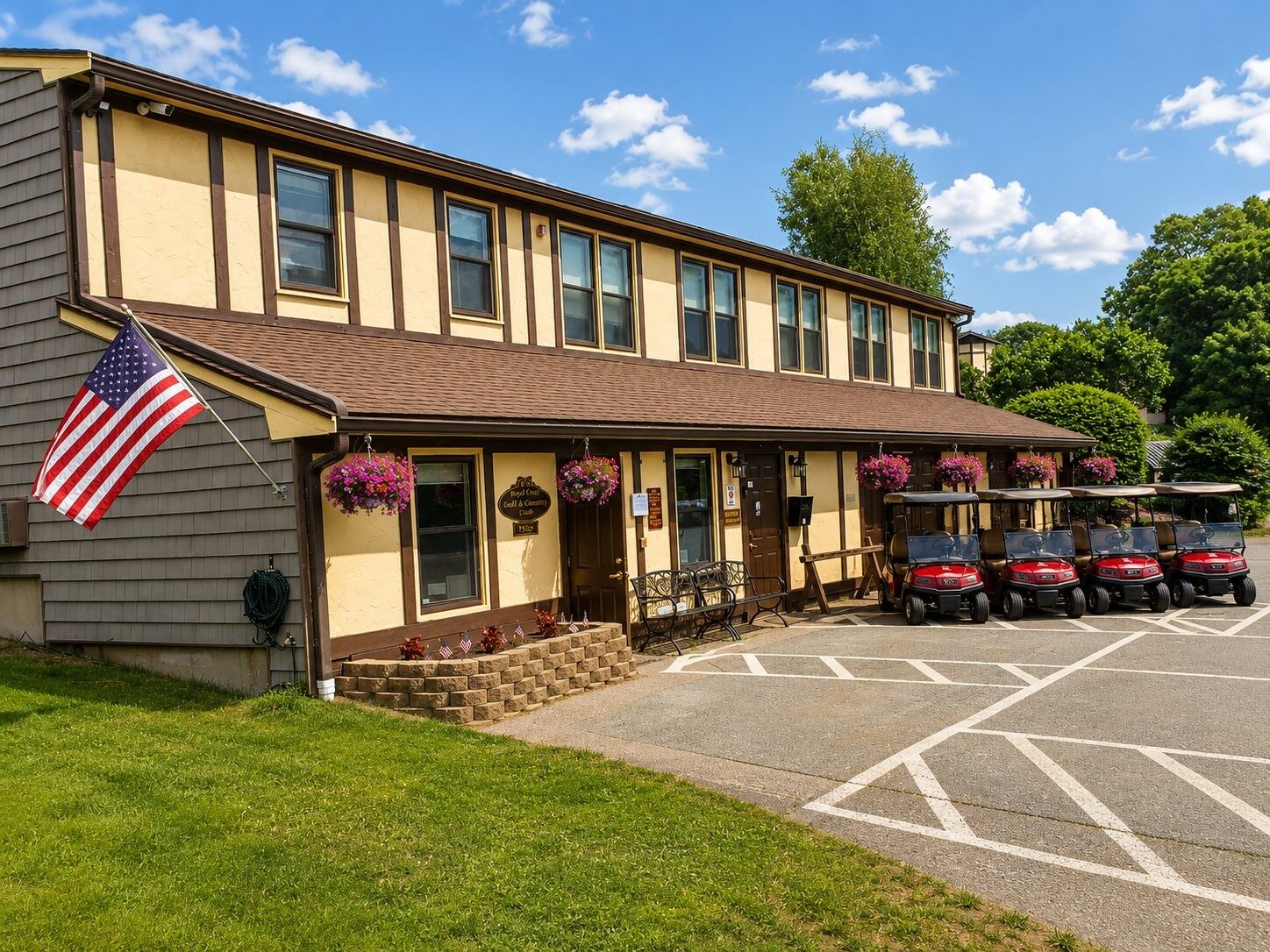 The Royal Crest clubhouse with flower baskets, flag, and golf carts